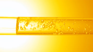 Transparent liquid flows in glass tube creating bubbles