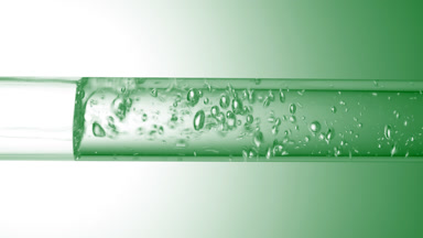 Transparent liquid flows in glass tube creating bubbles