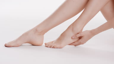 Female model touches her heel and leg sitting on the floor
