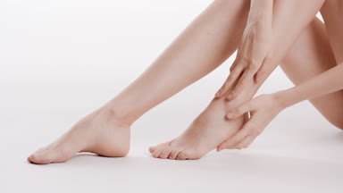 Female model touches her foot and leg sitting on the floor