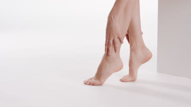 Female model touches her smooth legs sitting on white platform