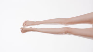Slim woman moves her crossed smooth legs doing leg scissors