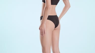 Woman touches hips and put hands on them turning to the camera