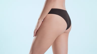 Slim woman in black underwear strokes and touches her smooth hip