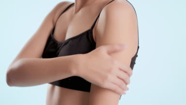Woman touches shoulder and chest looking at camera and smiling