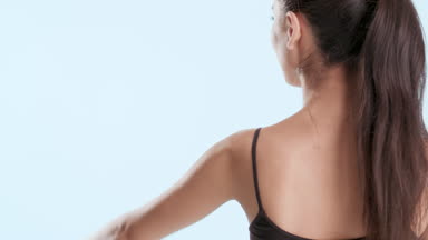 Slim beautiful woman with ponytail raises hands touching them