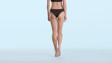 Woman in black underwear walking away from camera on tiptoes