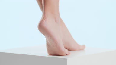Woman touches her tiptoe foot on the white cube platform