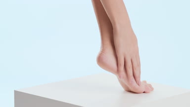 Woman touches her tiptoe foot and leg on the white cube platform