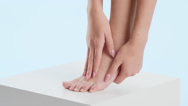 Woman strokes her tiptoe foot and leg on the white cube platform