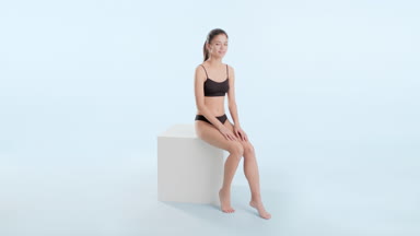 Asian slim woman touches hips sitting and put hands on podium