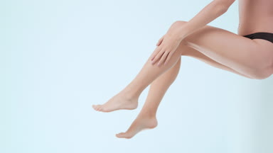 Gorgeous young slim lying woman touches moving leg and belly