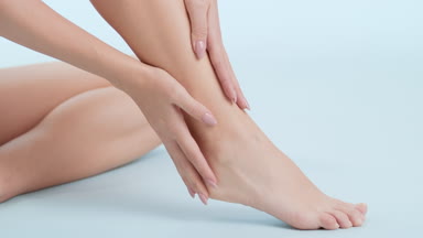 Gorgeous slim woman strokes foot and leg sitting on the floor