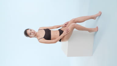 Asian slim woman touches hips sitting and put hands on podium
