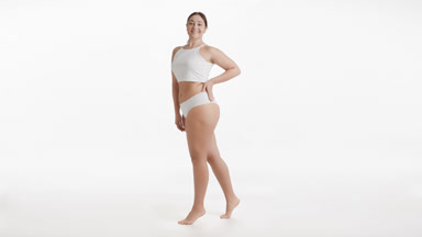 Plus size woman stands on tiptoes and puts hand on waist smiling
