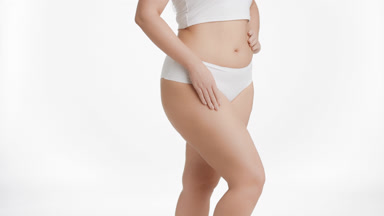 Plus size woman strokes thigh and puts hand on waistline turning