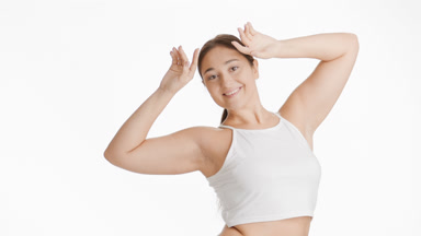 Plus size woman in white top raises hands up to head smiling