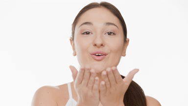 Plus size woman with long dark hair in ponytail blows a kiss