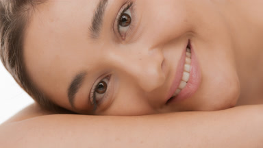 Beautiful young woman puts head on bent smooth arm smiling