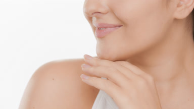 Young good-looking woman strokes her chin and jaw line smiling