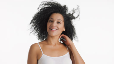 African woman turns to camera smiling and touching curly hair