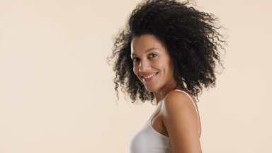 African American woman with curly hair moves her head up smiling