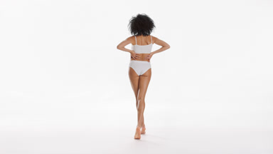 African American slim woman strokes hips and puts hands on waist