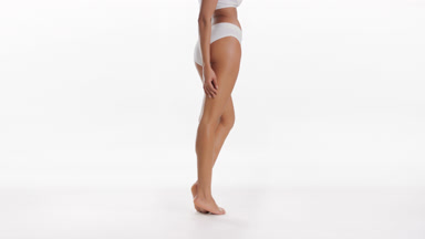 African American slim woman touches thigh standing on tiptoes