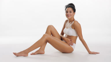 African woman strokes her leg and looks at the camera smiling