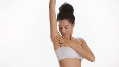 Cute African woman with black hair in bun strokes arm and armpit
