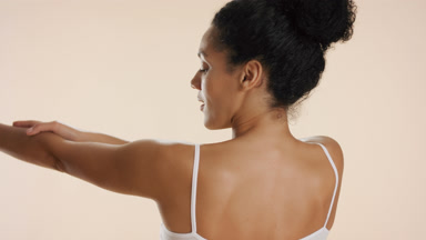 Slim African dark-haired woman with bun hairstyle strokes arms