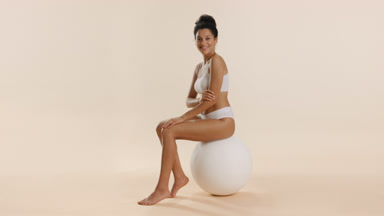 African woman strokes arm, puts hands on knee sitting on ball