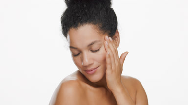 Young cute slim African woman strokes smooth face enjoying it