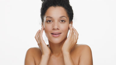 African American woman strokes face and looks at camera smiling