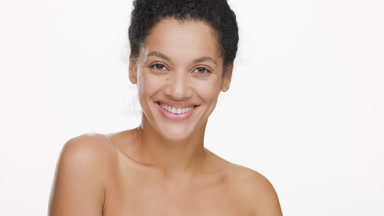 African woman with black curly hair turns head to camera smiling