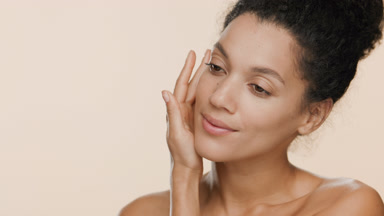 Young pretty African woman strokes face and turns head smiling
