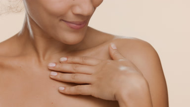 Young slim woman strokes clavicles turning head and smiles wide
