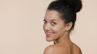 African woman with bare shoulders smiles and turns going away