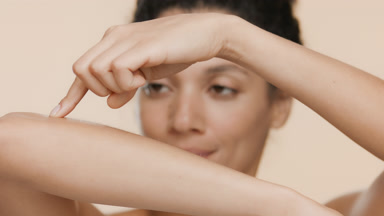 African American young slim woman strokes smooth forearm smiling