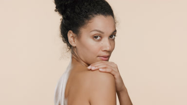 Young slim African American woman strokes shoulder turning away