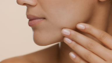 Extreme close-up of good-looking slim woman strokes her jaw line
