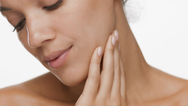 Attractive African woman strokes jaw line and turns head smiling
