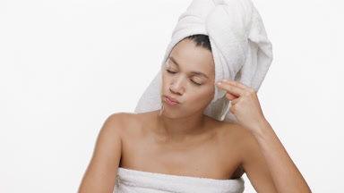 Woman with a towel on head makes hand gun gesture shooting head
