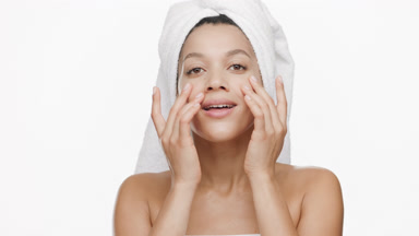 African American woman with towel on head touches face tapping