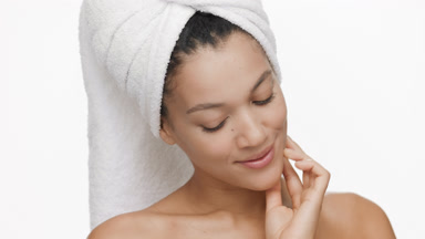 African woman with a towel on hair strokes jaw line turning head