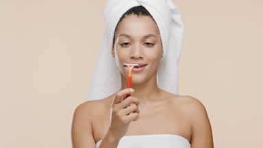 Cute African woman with a towel on head throws away orange razor