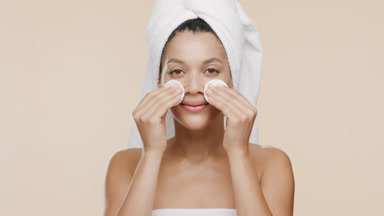African woman strokes nose and cheeks with cotton pads smiling