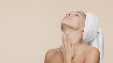 Cute African slim woman with a towel on hair stokes neck smiling
