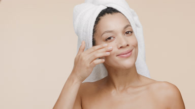 Beautiful African woman with towel on hair stokes cheek smiling
