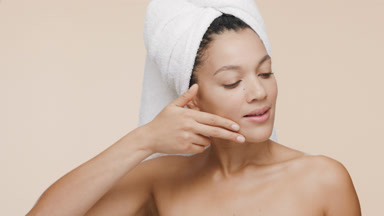 African young woman with towel on head stokes jaw line smiling